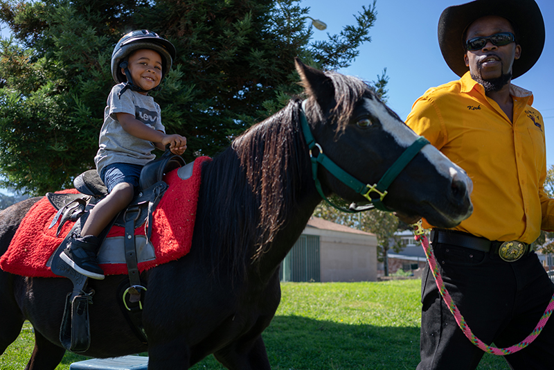 Boy on horse with Oakland Black Cowboys at Block Party